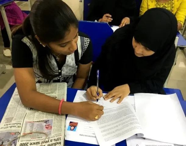 A FirstLeap facilitator helping a woman complete a form